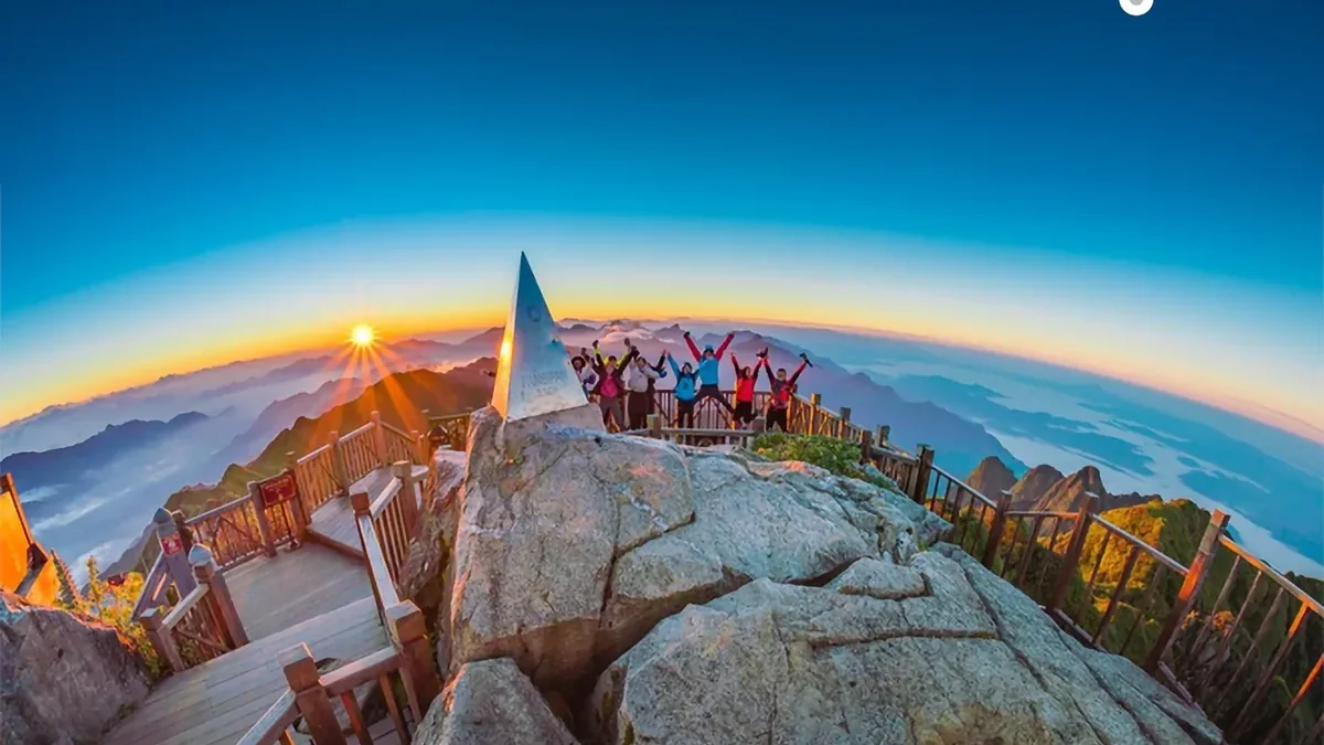 A Morning Vietnam small group celebrating sunrise at the Fansipan summit above a sea of clouds