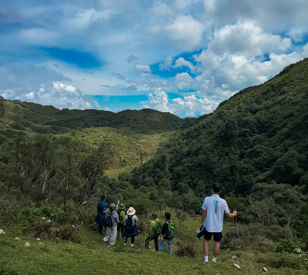 Trekkers pausing above a green valley