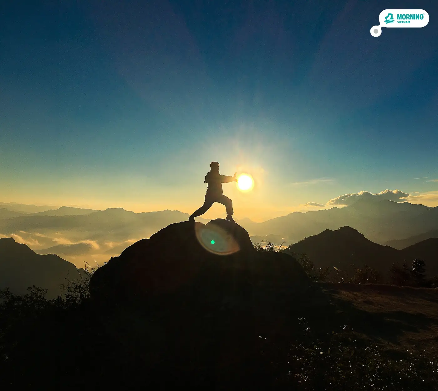 Trekker silhouetted on a rock at sunrise