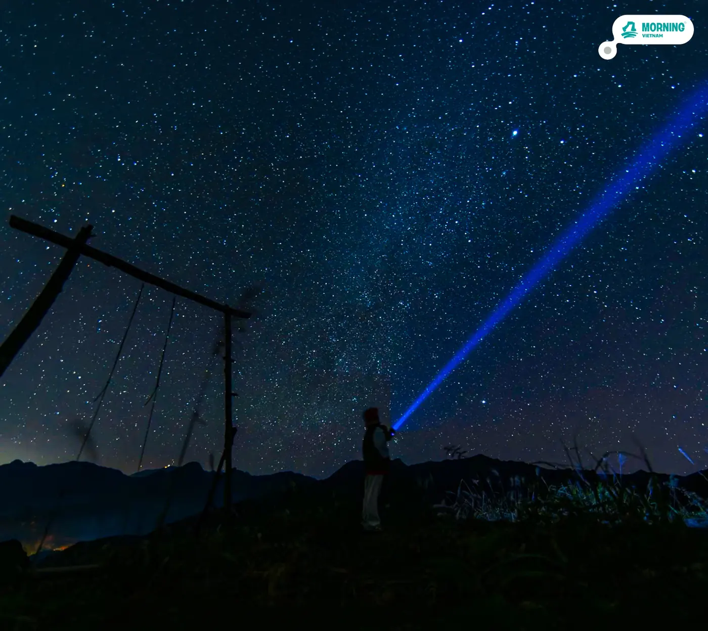 Night sky and a headlamp beam beside the summit swing